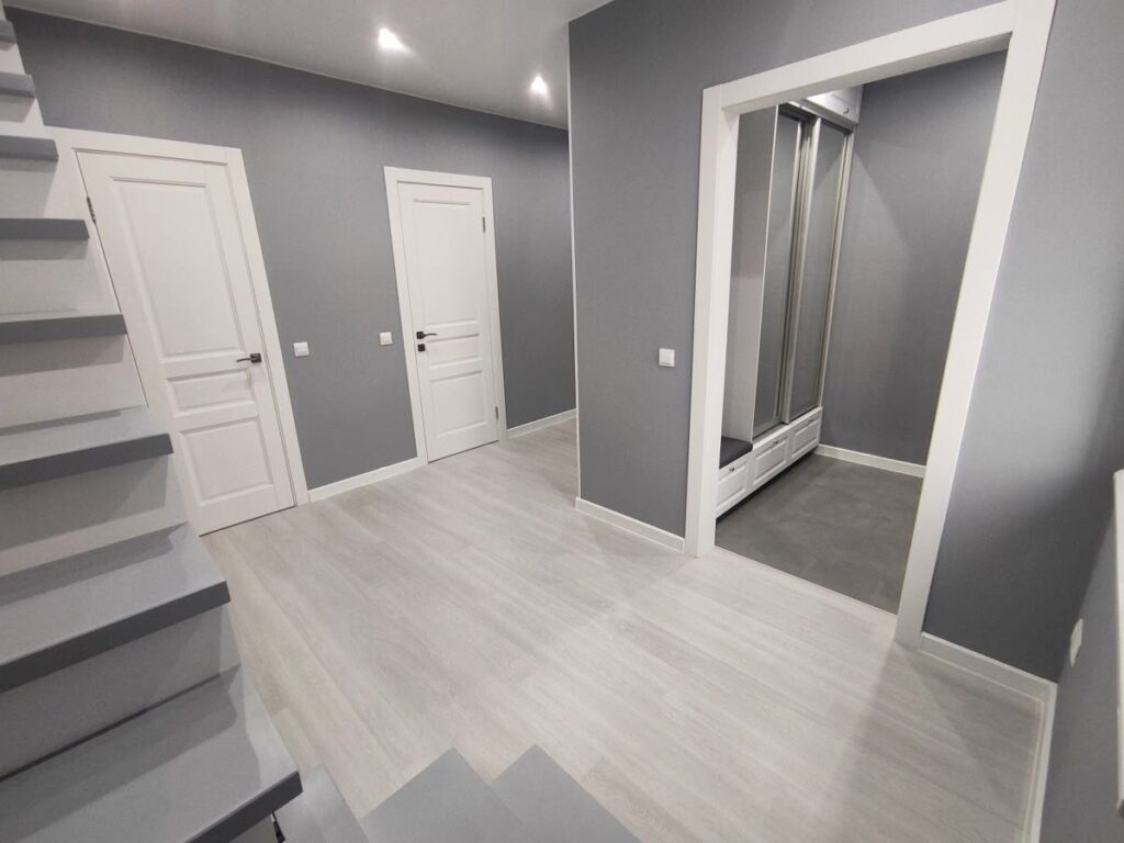 Freshly painted grey hallway with white doors and stair trim