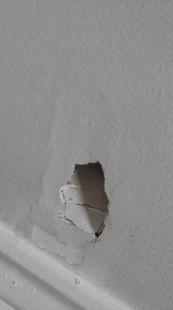 Drywall hole above the baseboard in a Durham Region hallway in Durham Region