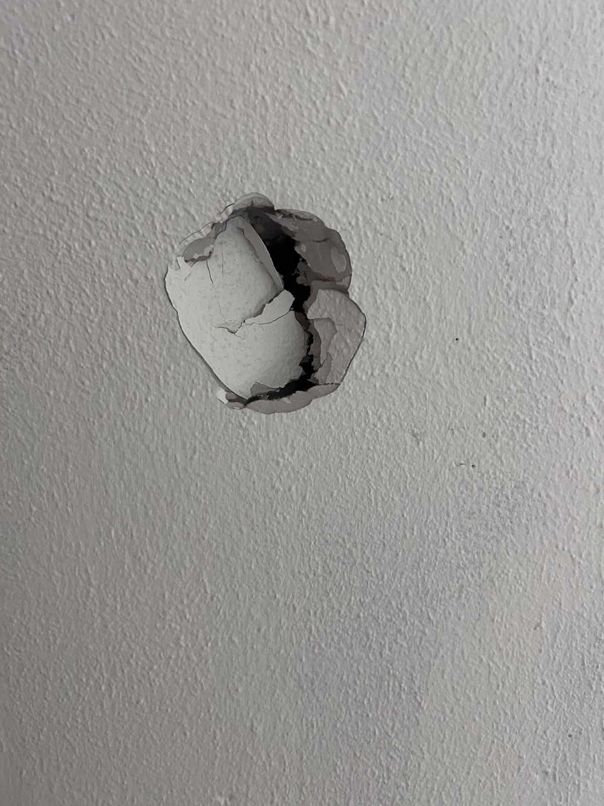 Doorknob burst through textured drywall in a London rental