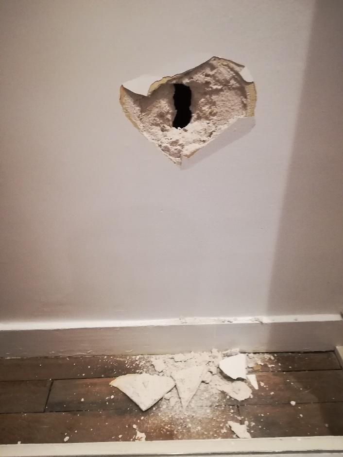Drywall hole with debris on the floor of a Simcoe County chalet in Simcoe County