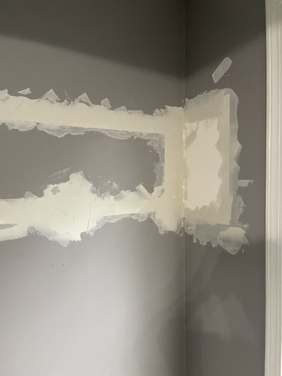 Drywall corner patch coated with joint compound during repair by IntraBuild